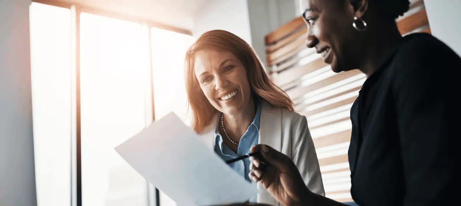 two women smiling looking at paper